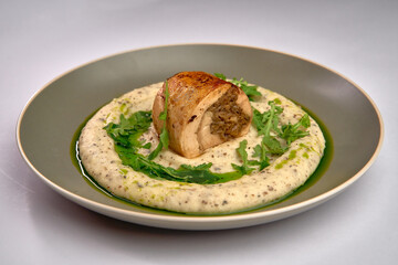Deliciously Plated Chicken Dish Featuring Savory Stuffing Nestled on Creamy Purée with a Drizzle of Green Herb Oil and Fresh Greens for Garnish