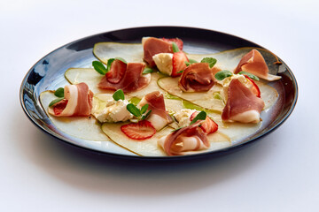 A Culinary Delight Featuring Delicate Prosciutto and Sweet Strawberries on a Bed of Thinly Sliced Pears, Artfully Presented on a Glazed Plate