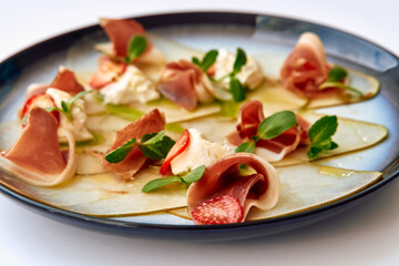 An Artful Presentation of Delicate Culinary Ingredients Featuring Prosciutto, Creamy Cheese, and Fresh Herbs on a Stylish Plate