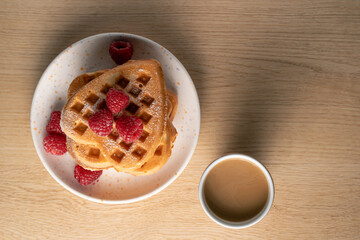 top-down view of heart-shaped waffles and coffee on wooden table