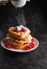 Hand sifting powdered sugar over waffles