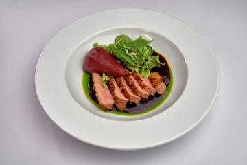 Elegant Plate of Sliced Duck Breast Accompanied by Stewed Pear and Fresh Greens Drizzled with a Rich Sauce on a Fine Dining Dish