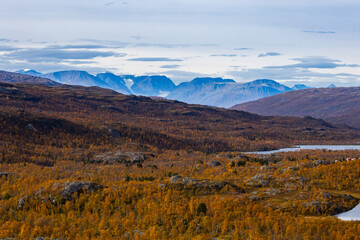 Autumn landscape of Kilpisjarvi, Finland, showcasing colorful foliage, serene lakes, and majestic mountains in the background.