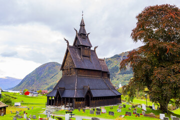 Hopperstad Stavkyrkje in South Norway, a historic wooden church surrounded by autumn trees and a peaceful graveyard.