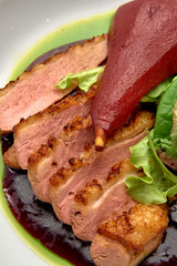 A Culinary Delight: Sliced Duck Breast Elegantly Plated with Poached Pear and Rich Sauce for an Exquisite Dining Experience