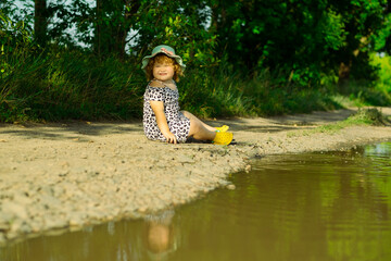 Child Enjoys Sitting by a Puddle on a Sunny Day in a Green Park Surrounded by Nature