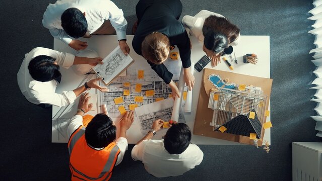 Top down view of skilled architect engineer working together to plan building at meeting table. Aerial view of smart interior design looking at project plan while check mistake point. Alimentation.
