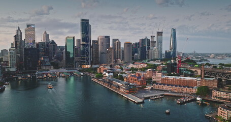 Australia, Sydney: CBD skyline reflecting on calm water in cloudy sunset, modern buildings...