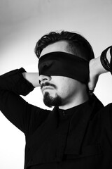 A man with his eyes blindfolded. Studio photo