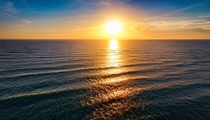 Obraz premium aerial perspective reveals the shimmering rippling surface of the sea illuminated by the setting sun with the light streaking across the water like liquid gold