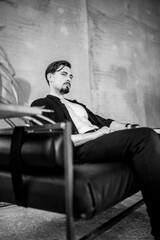 Stylish black and white men's photo shoot with an ethnic mask. The man is wearing a stylish suit