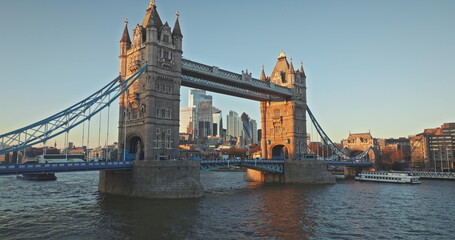 London: Tower Bridge against a backdrop of modern skyscrapers city during sunset, boats sailing on...
