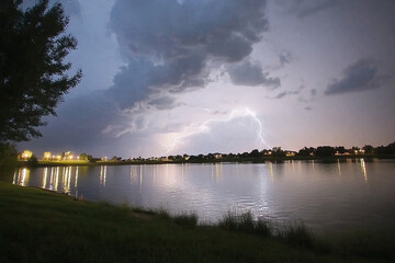 Dramatic lightning strikes over a calm lake during a storm