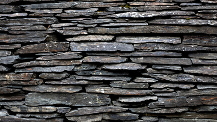 Horizontal view of natural slate stone wall with rough texture  
