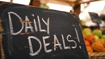 Rustic chalkboard sign at a market with "Daily Deals!" in white chalk font