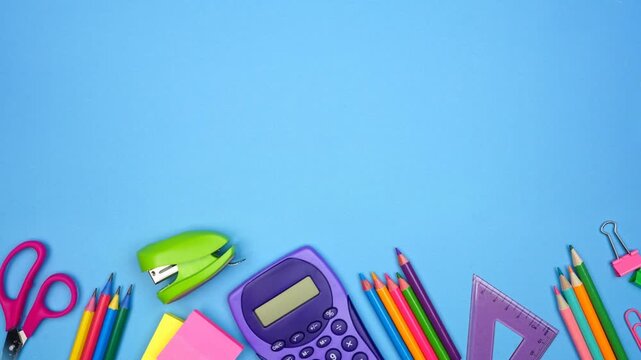 Colorful school supplies moving bottom border. Top view stop motion loop video over a blue background. Back to school concept.