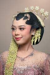 A beautiful Asian bride wearing traditional Javanese kebaya and intricate hair accessories, smiling...