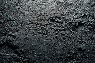 Obraz premium A dark, rough, and textured concrete surface with a gritty appearance, suitable for grunge or industrial backgrounds