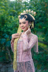 Elegant Asian woman wearing traditional Javanese bridal kebaya with jasmine hair accessories,...
