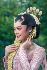 Graceful Indonesian woman in traditional Javanese bridal attire, wearing elegant jasmine hair...
