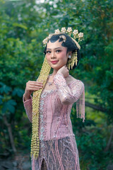 A beautiful Asian bride wearing a traditional Javanese kebaya and elegant hair accessories,...