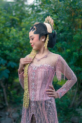 Graceful Asian bride in traditional Javanese kebaya, adorned with golden accessories and jasmine...