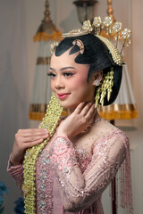 Graceful Indonesian bride in elegant pink kebaya with detailed embroidery and traditional floral...