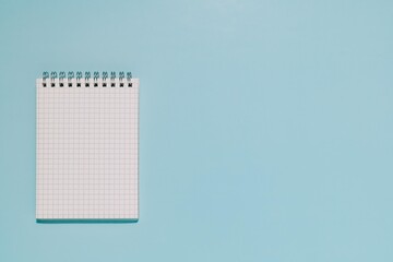 An open, blank grid notepad on a clean, light blue background. Perfect for themes of planning, ideation, learning, and new projects.