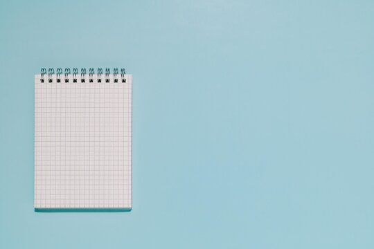 An open, blank grid notepad on a clean, light blue background. Perfect for themes of planning, ideation, learning, and new projects.
