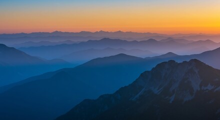 Obraz premium Layered Blue Mountain Range at Sunset with Orange Sky