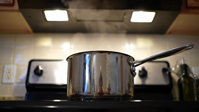 Stainless steel pot steams on stovetop with warm kitchen lights above