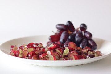 Black seedless grapes and freshly sliced grape pieces on a white plate