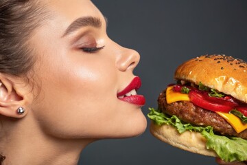Woman about to eat a tasty cheeseburger, side profile close up.