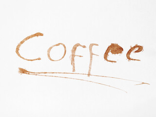 The word Coffee artfully written in coffee stains on white paper.