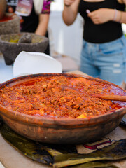 Clay casserole filled with beef birria at a street food stall in Mexico.