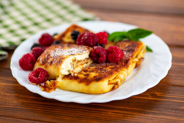 Golden cheese pancakes with berries on plate