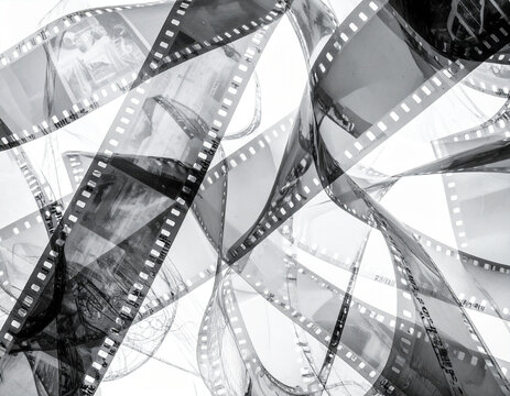 Abstract tangle of processed 35mm film strips in black and white, showing sprocket holes and glimpses of frames. Perfect for retro or photographic backgrounds.