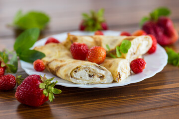 Homemade pancakes with cottage cheese filling and berries on a wooden table