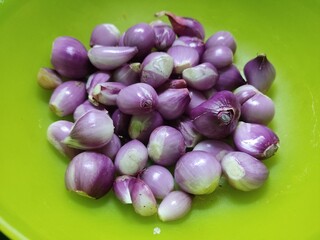 pile of peeled shallots in a round green plastic container