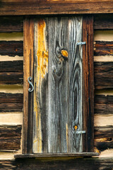 A shuttered window on a log cabin