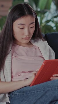 Asian young attractive woman in casual outfit sitting ofa using tablet application network internet staying home with her pet. Bulldog puppy. Family together.