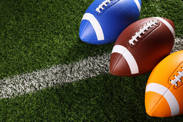 A textured American football resting on the green artificial turf with white line. College Football