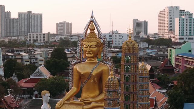 Golden buddha statue in wat paknam phasi charoen temple with bangkok city skyline in the background.