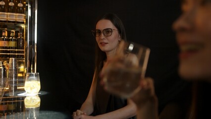 Focusing on beautiful woman in soda drink accompanied by friends at luxurious bar nightclub. Smart bartender providing excellent service beverage menu at vibrant nightlife party atmosphere. Vinosity.