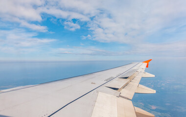 Obraz premium View from the airplane window at a beautiful cloudy sky and the airplane wing