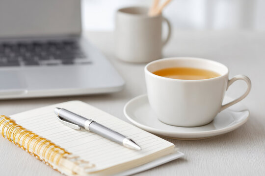 Quiet workspace featuring planner, pen, laptop, and cup of tea fostering productivity and focus in a serene environment