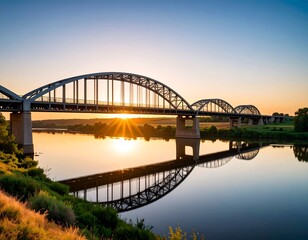 Fototapeta premium Sunrise over a metal arch bridge reflecting on a calm river