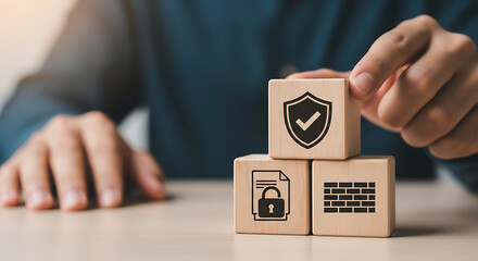A hand is placing a wooden block with a shield icon, symbolizing cybersecurity and protection