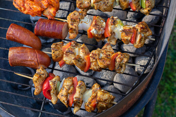 Grilled chicken skewers with vegetables on barbecue grill over hot coals, close-up of seasoned kebabs with onion and bell pepper during outdoor cooking.
