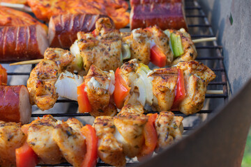 Grilled chicken skewers with vegetables on barbecue grill over hot coals, close-up of seasoned kebabs with onion and bell pepper during outdoor cooking.